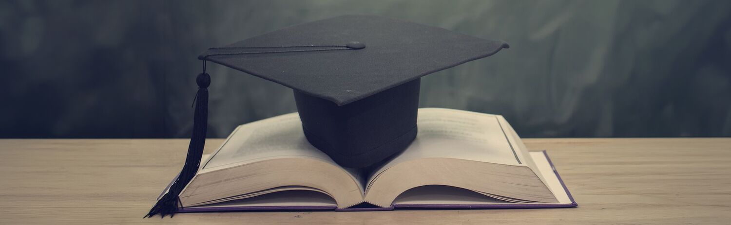 A graduation cap resting on an open book